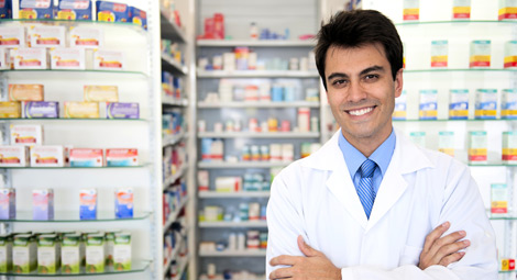 Male pharmacist stood in front of shelves of medication